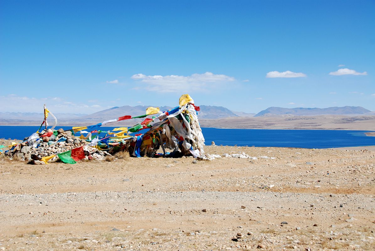 27 Lake Manasarovar Behind Prayer Flags On Ridge Between Lake Manasarovar And Lake Rakshas Tal After driving past the southwestern corner of Lake Manasarovar, we crested a small ridge with prayer flags and a view back to Lake Manasarovar.